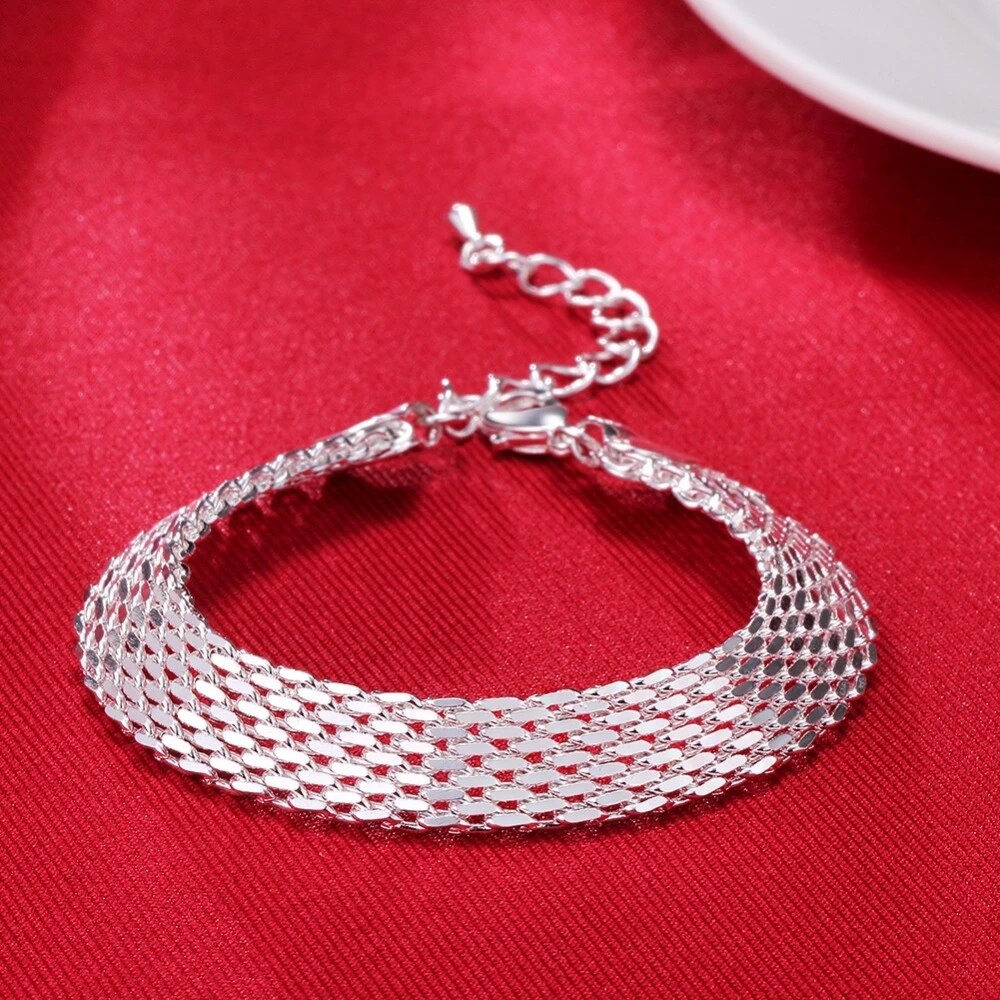 Silbernes Armband auf rotem Stoff, elegantes Schmuckdesign, verstellbare Kette, Damenaccessoire.