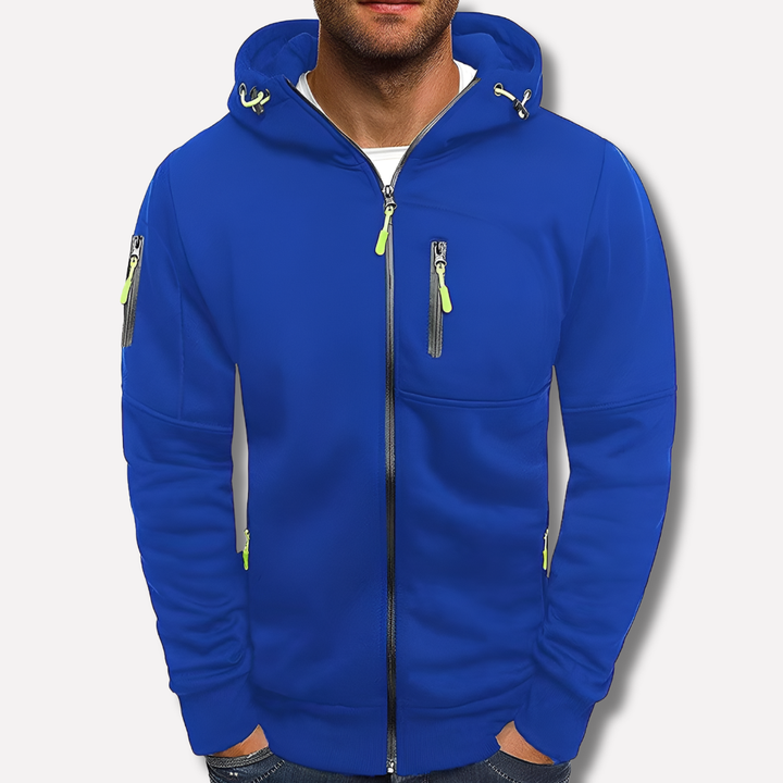 Modrá mikina na zip s kapucí na muži před světlým pozadím, detail zipové kapsy na hrudi a na rukávu. 2