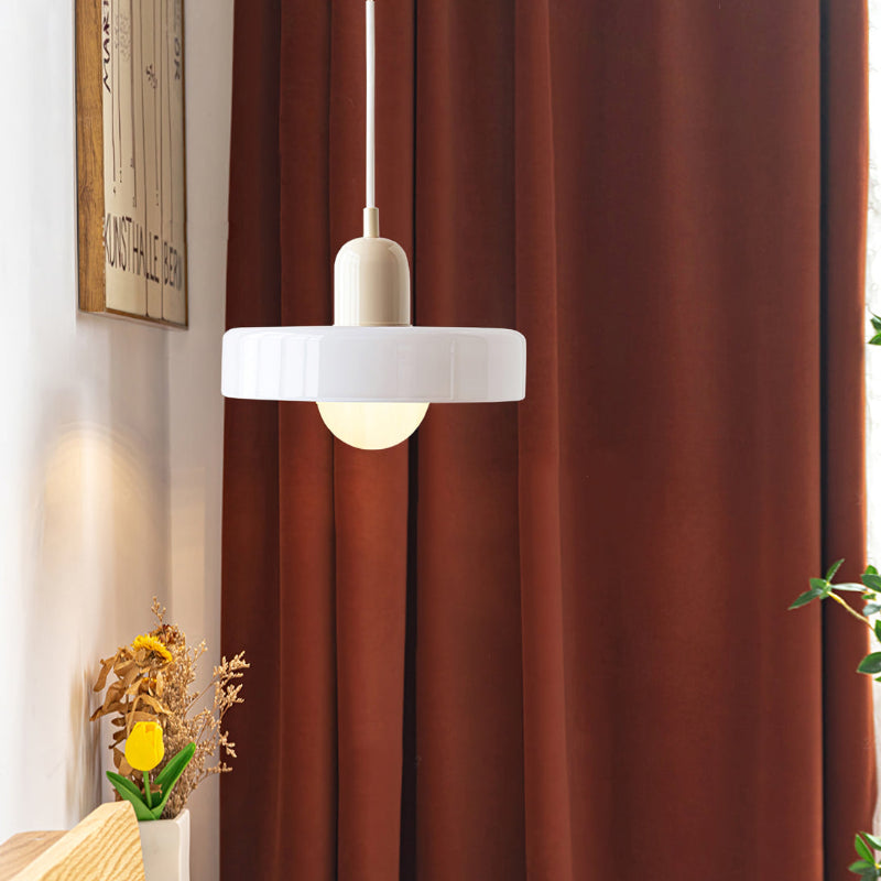Moderne weiße Glas-Pendelleuchte vor braunem Vorhang, stilvolle Innenbeleuchtung.