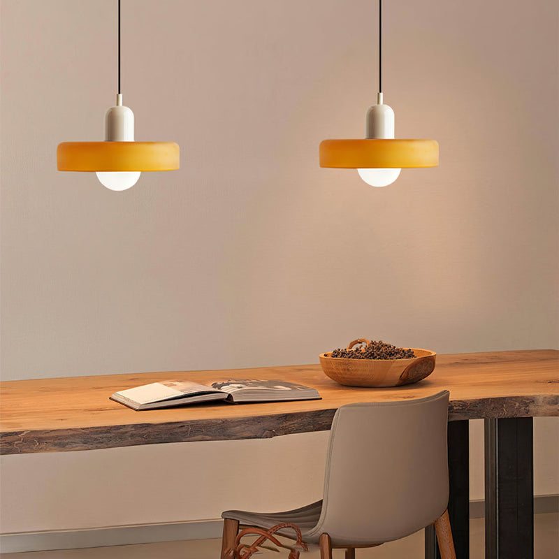 Moderne bunte Glas-Pendelleuchte über Holztisch, gelber Lampenschirm, Inneneinrichtung.