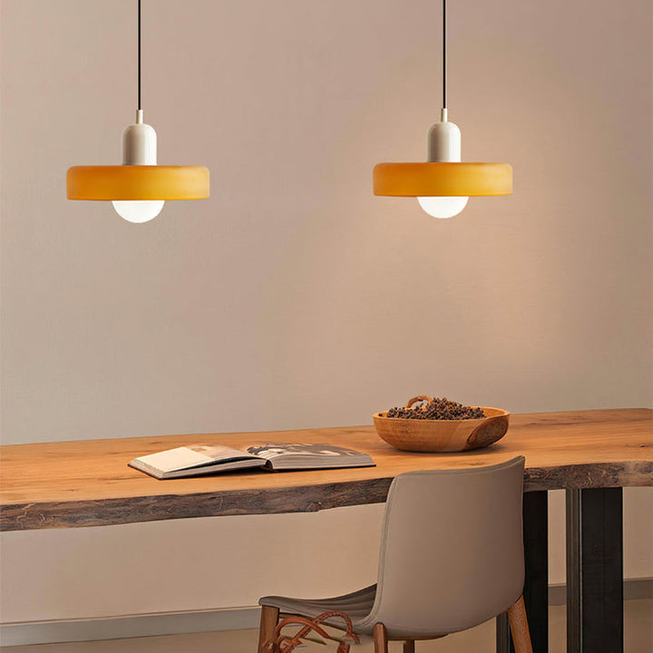 Moderne bunte Glas-Pendelleuchte über Holztisch, gelber Lampenschirm, Inneneinrichtung.