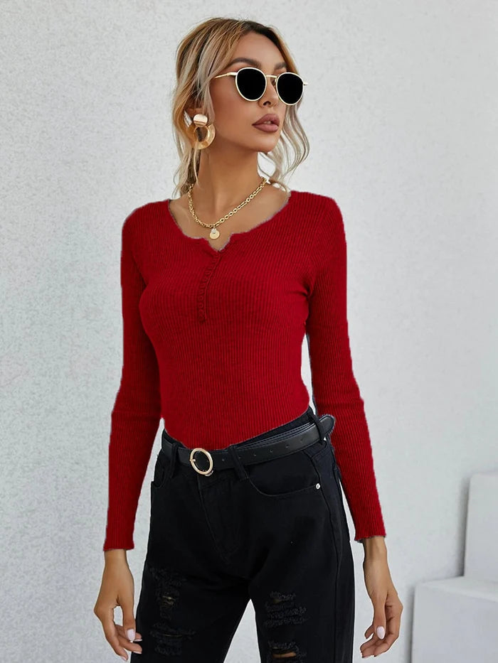 Frau in rotem V-Ausschnitt-Pullover, schwarze Hose, Sonnenbrille, modisch, elegant.