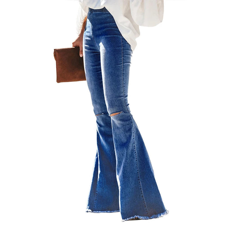 Frau in blauen Vintage-Schlagjeans mit Knöpfen, weiße Bluse, braune Clutch.