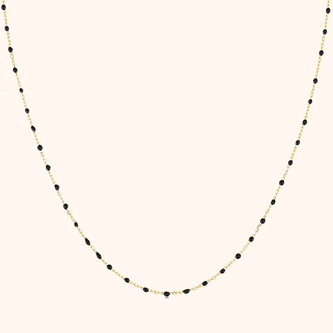 Goldene Halskette mit schwarzen Perlen, elegantes Schmuckdesign, Damenaccessoire.