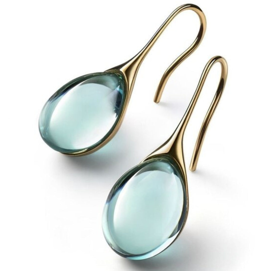 Goldene Ohrringe mit blauen Edelsteinen, elegantes Schmuckdesign, modische Accessoires.