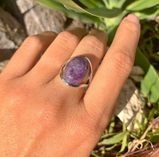 Silberring mit ovalem Amethyst, getragen an Hand, Schmuck, lila Edelstein, Naturhintergrund.
