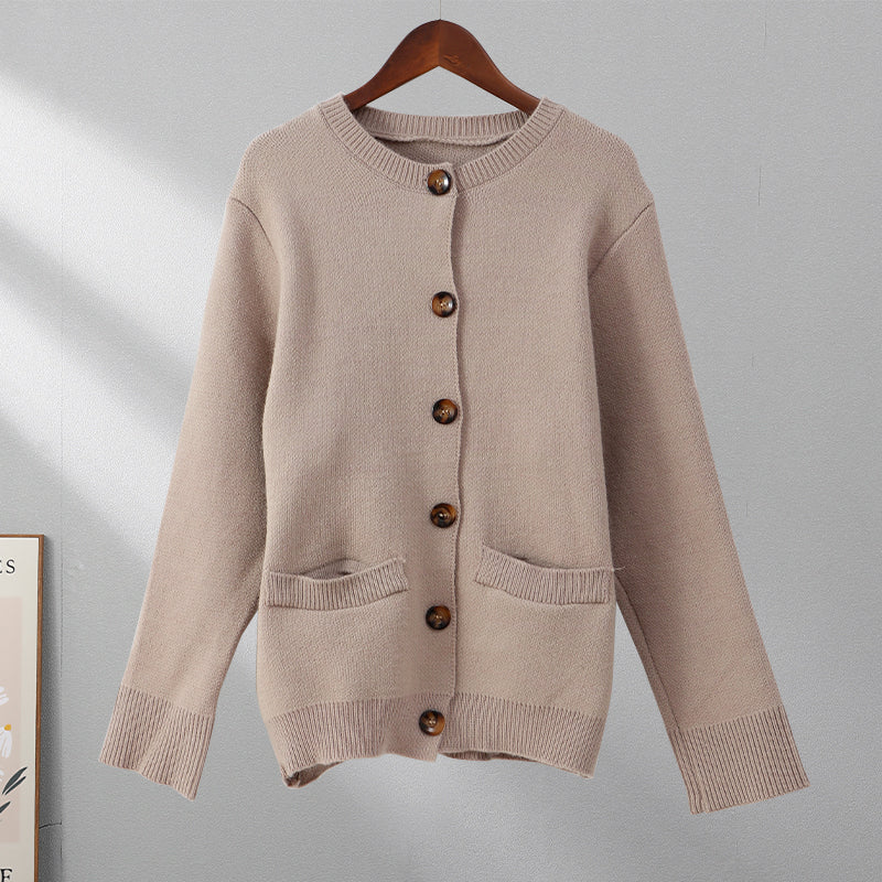 Beige Strickjacke mit Knöpfen, Damenmode, weiches Material, lässiger Stil, hängend auf Bügel.