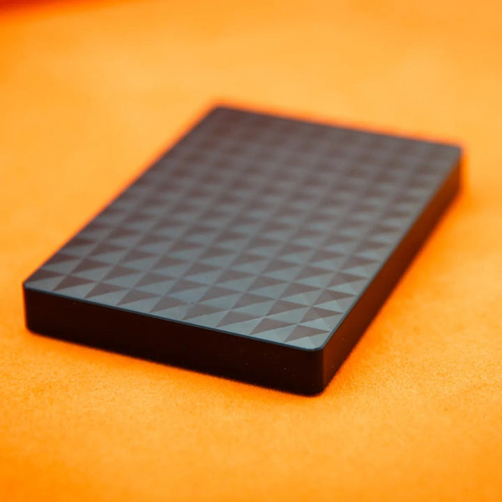 Černý plochý disk s pyramidovým vzorem na oranžovém podkladu, detail z boku 4