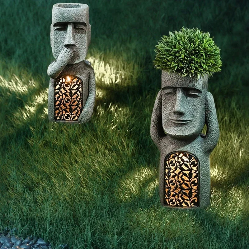 Zwei graue Moai-Blumentöpfe mit LED-Licht, Garten-Dekoration, Gras, Nachtaufnahme.