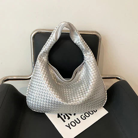 Silberne geflochtene Handtasche auf schwarzem Stuhl, modisches Accessoire, Damenmode.