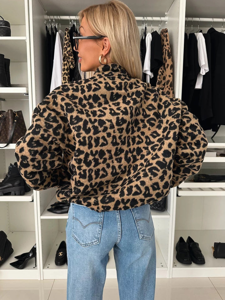 Záda bundy s leopardím potiskem na modelce v džínách, vidět stojáček a nadýchané rukávy se staženými manžetami. 2
