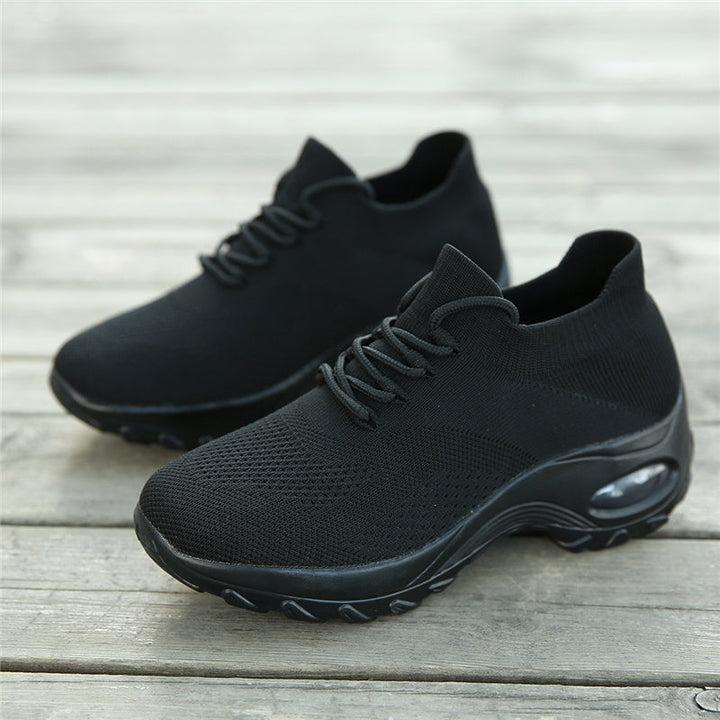 Schwarze Sportschuhe mit atmungsaktivem Mesh-Obermaterial auf Holzboden.