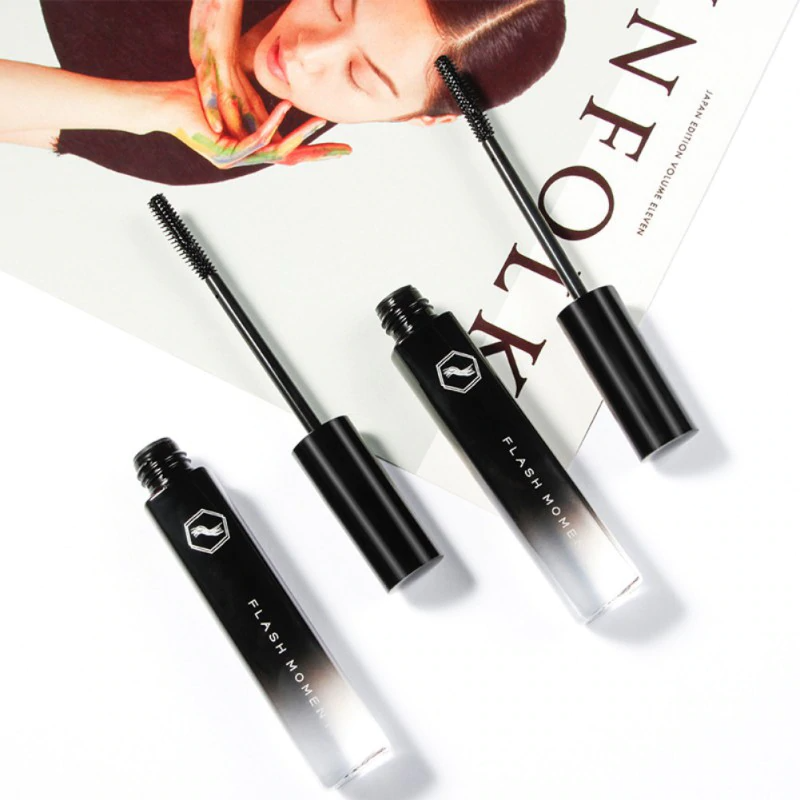 Schwarze Flash Move Mascara, offene und geschlossene Tuben, auf Magazin liegend.