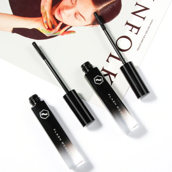Schwarze Flash Move Mascara, offene und geschlossene Tuben, auf Magazin liegend.