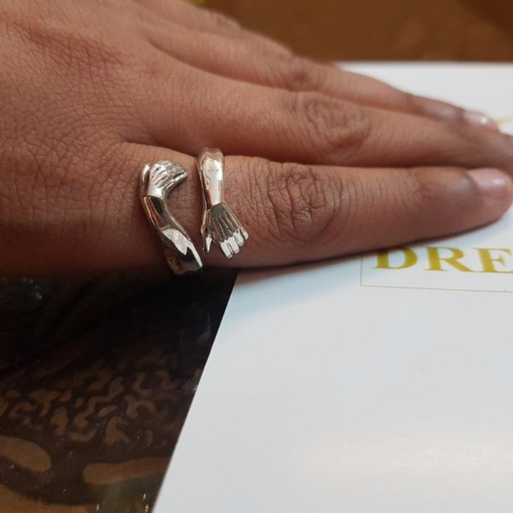 Silberner Ring in Handform auf Finger, einzigartiges Schmuckdesign, modischer Statement-Ring.