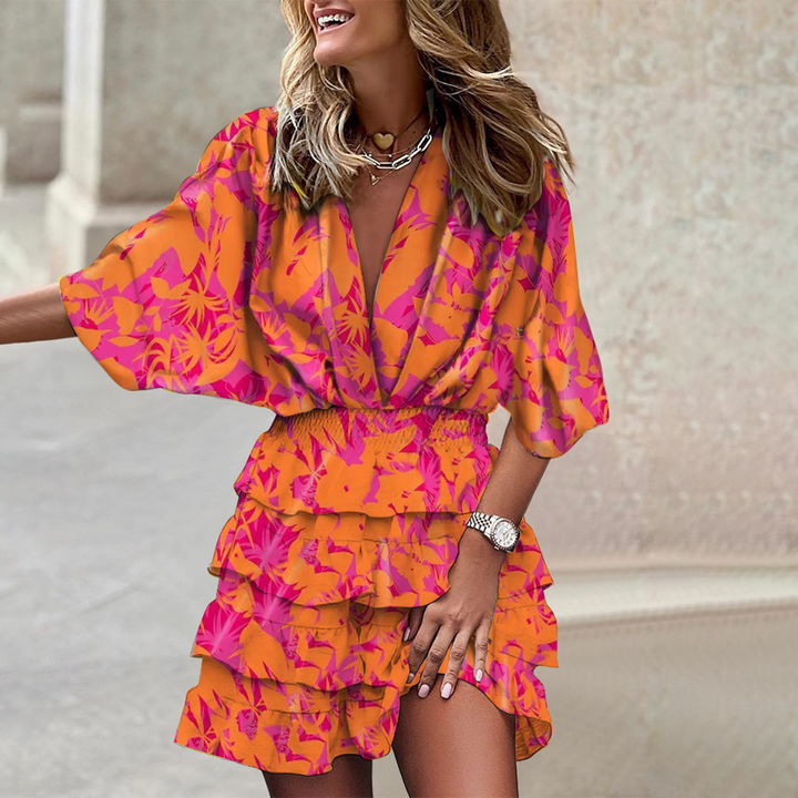 Frau in orange-pinkem Blumenkleid, Rüschen, lächelnd, modisch, Sommermode, draußen.