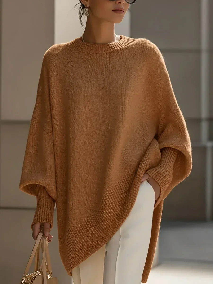 Hnědooranžový oversized svetr s asymetrickým žebrovaným lemem na modelce v bílých kalhotách s kabelkou. 12