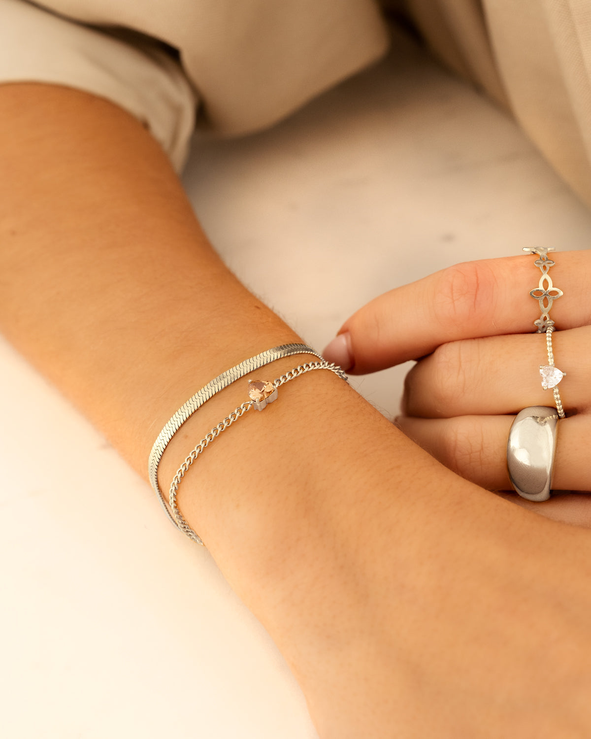 Silberne Armbänder und Ringe an Hand, eleganter Schmuck, modisches Accessoire, Nahaufnahme.