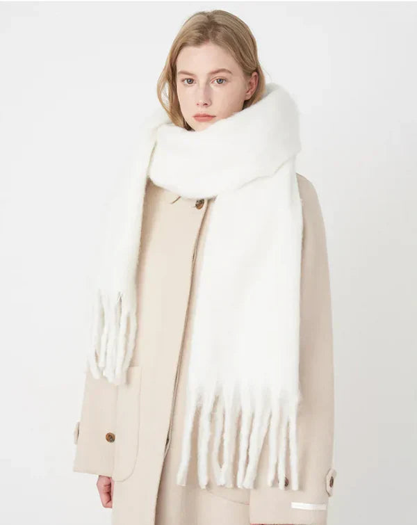 Frau mit weißem Wollschal und beigem Mantel, Wintermode, elegantes Accessoire, warm und stilvoll.