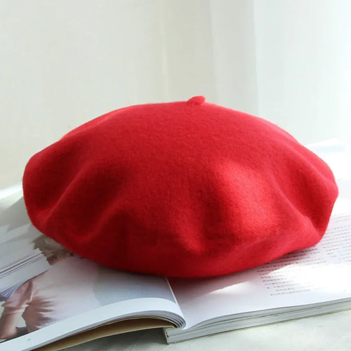 Roter Woll-Baskenmütze auf offenem Buch, stilvolles Accessoire, modisch, elegant.