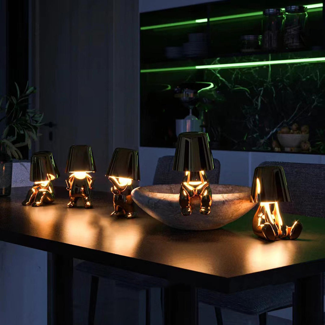 Fünf goldene Tischlampen in Form von Figuren auf einem Tisch, moderne Inneneinrichtung.