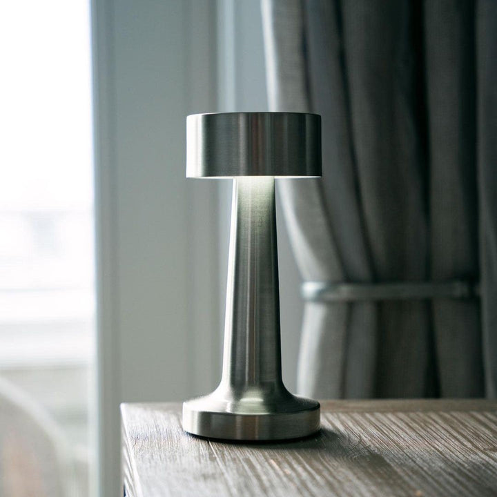 Moderne silberne Tischlampe aus Metall auf Holztisch, ideal für Restaurant oder Barbeleuchtung.