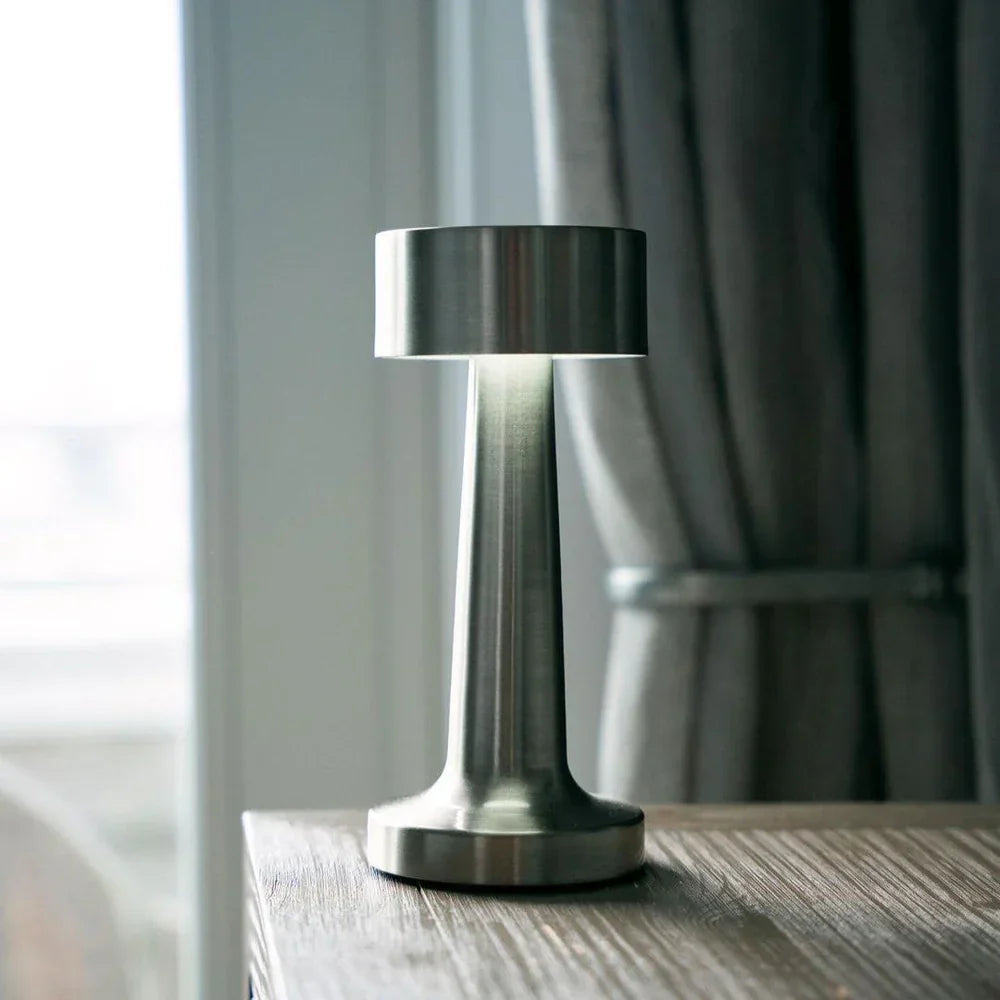 Moderne silberne Tischlampe aus Metall auf Holztisch im Restaurant, stilvolle Beleuchtung.
