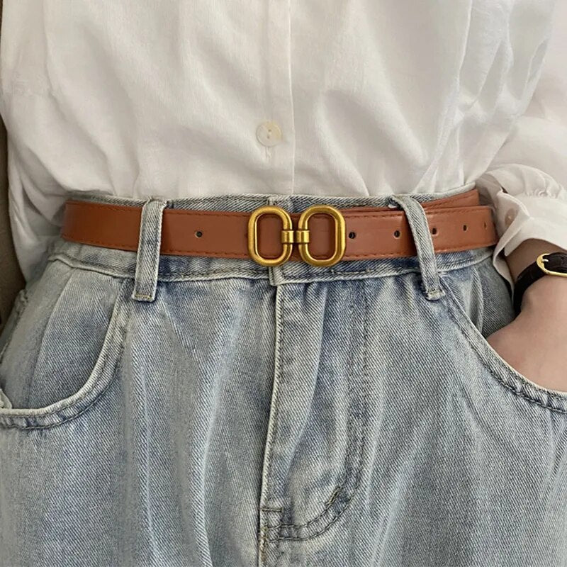 Brauner Ledergürtel mit goldener Schnalle, Retro-Design, getragen mit blauer Jeans.