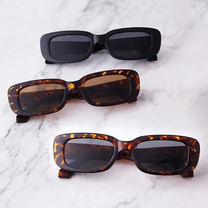 Drei Retro-Vintage-Sonnenbrillen, rechteckig, schwarz und Schildpatt, auf Marmortisch.