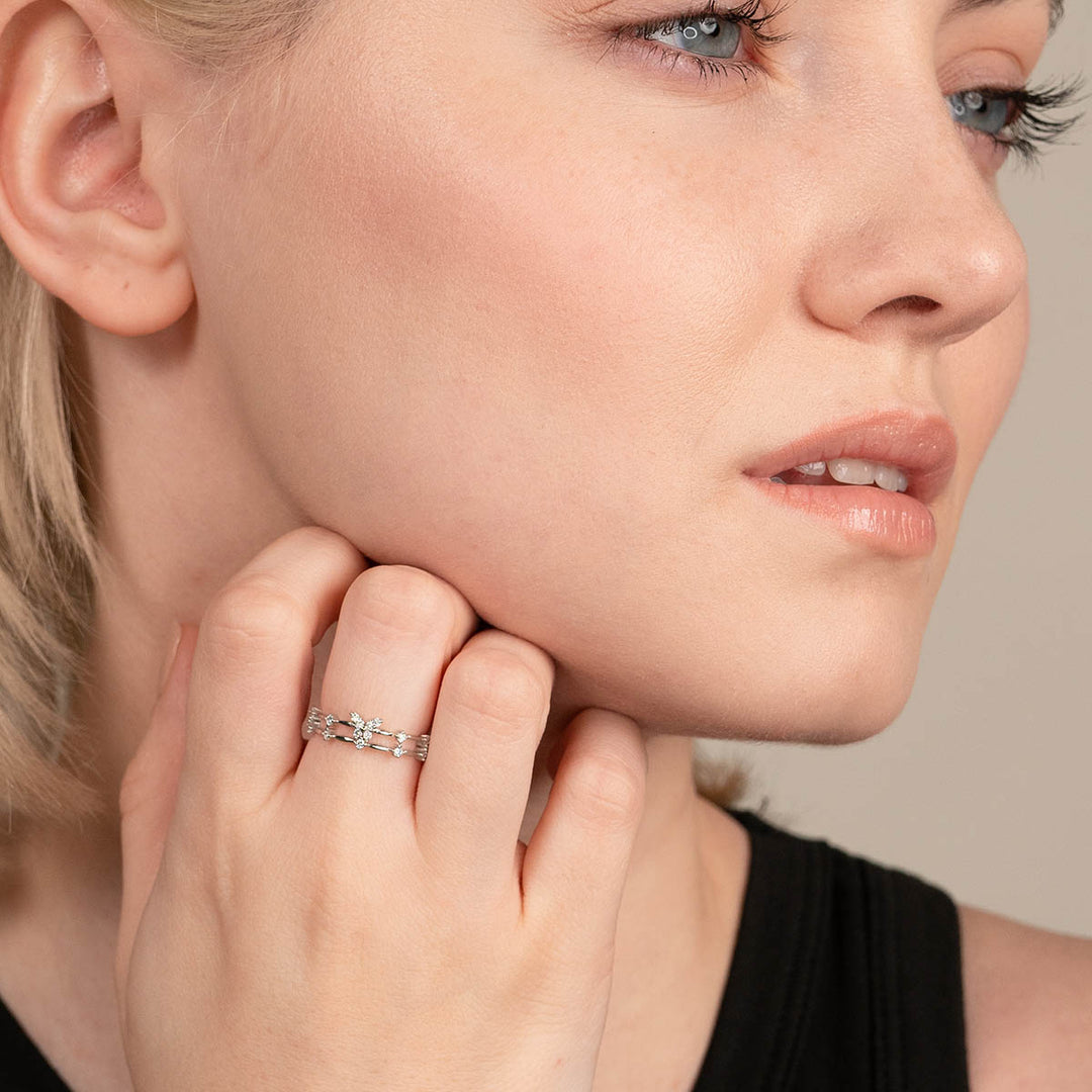 Frau trägt silbernen Ring mit Blumenmuster, eleganter Schmuck, Nahaufnahme.