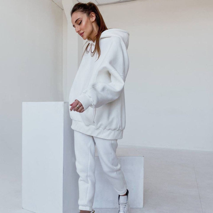 Frau in weißem Hoodie und Jogginghose, lässige Mode, bequeme Freizeitkleidung, minimalistisch.