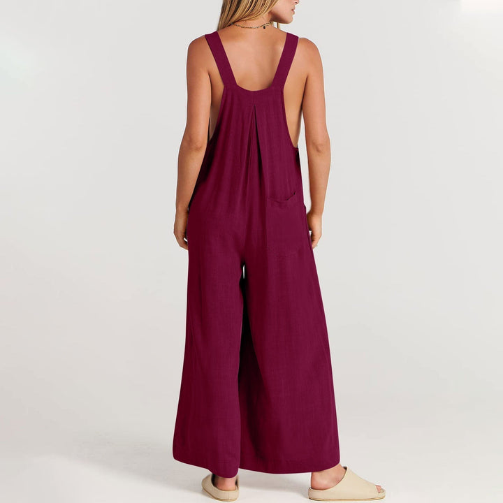 Frau in weinrotem Jumpsuit aus Leinen, Rückansicht, lässige Sommermode, barfuß.
