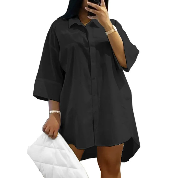Frau in schwarzem Oversize-Hemd, Handy in der Hand, weiße gesteppte Tasche, modisch.