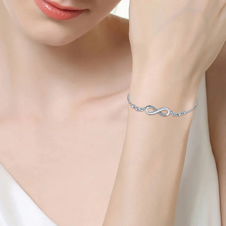 Silbernes Unendlichkeitsarmband am Handgelenk einer Frau, eleganter Schmuck, modisches Accessoire.