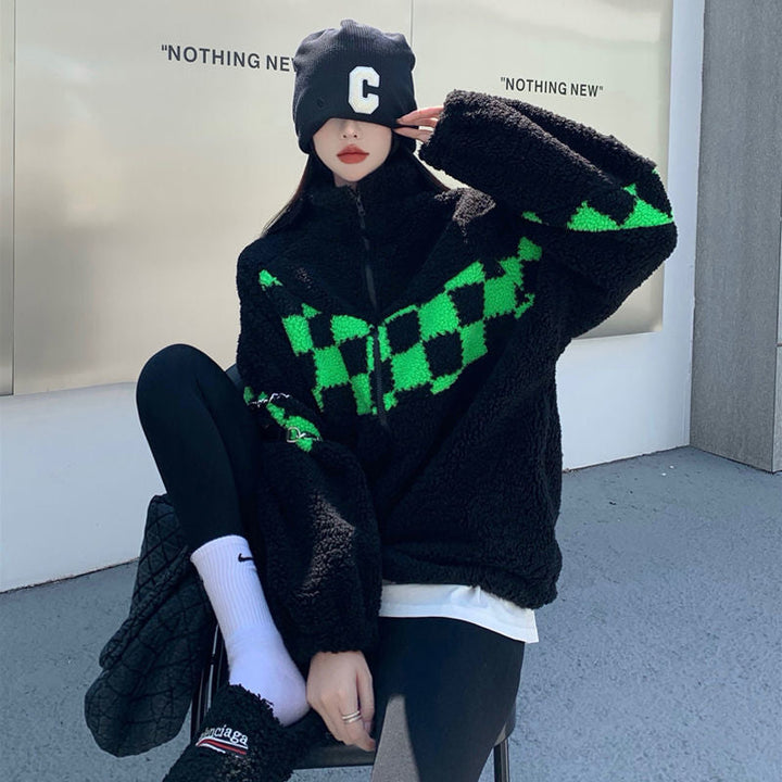 Frau in schwarzer Fleecejacke mit grünem Karomuster, schwarze Leggings, Mütze, lässiger Stil.
