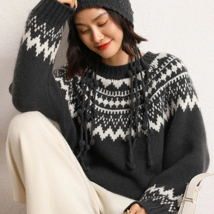 Frau in grauem Strickpullover mit Norwegermuster und Mütze, lächelnd, Wintermode.