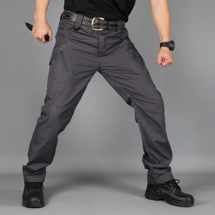 Mann in taktischer Hose, schwarz, mit Messer, Outdoor-Ausrüstung, robust, strapazierfähig.
