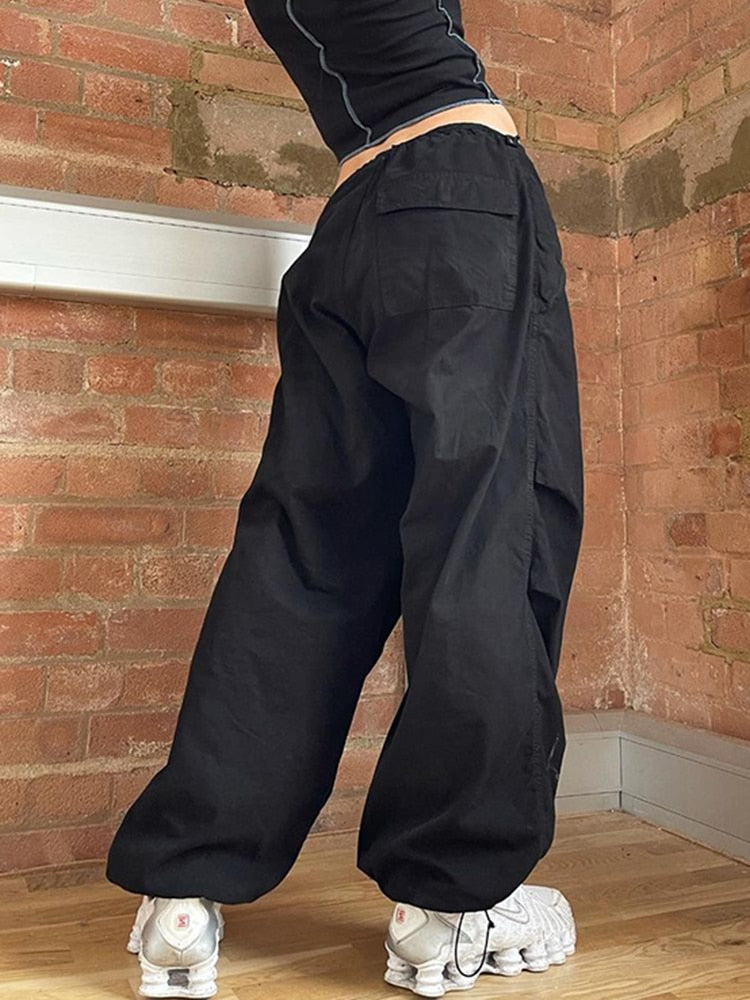 Schwarze Baggy-Hose aus Baumwolle, lässig, Unisex, Streetwear, Ziegelwand-Hintergrund.