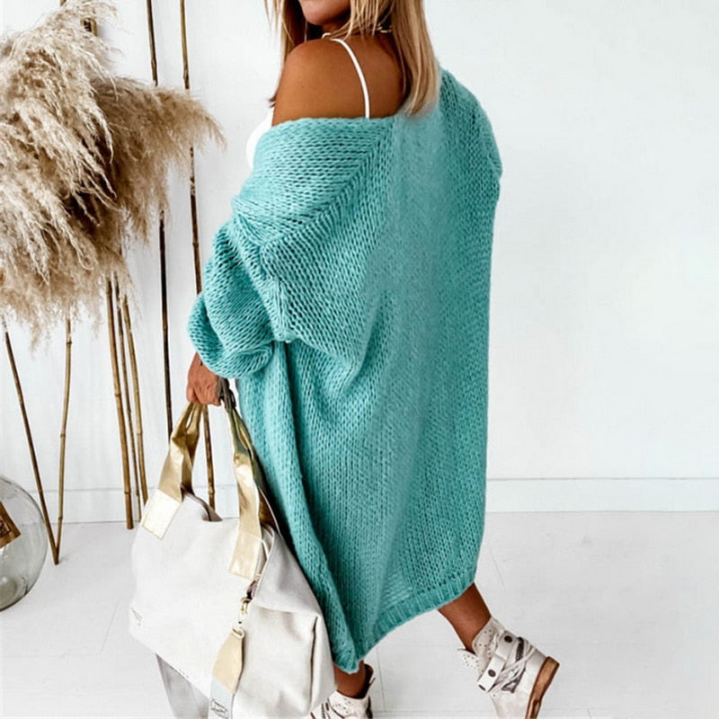 Frau in türkisfarbenem Strickcardigan mit weißer Tasche, modisch, lässig, Herbstmode.