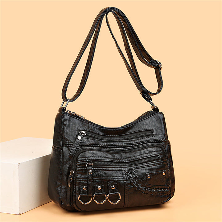 Schwarze Lederhandtasche mit Reißverschlüssen und Ringen, modisch und vielseitig.