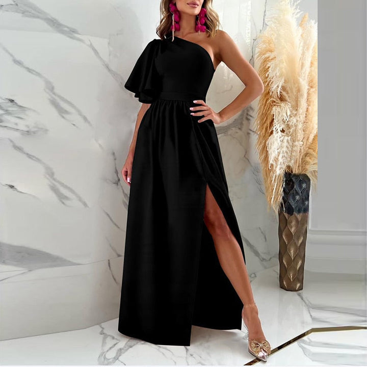 Frau im eleganten schwarzen Abendkleid mit asymmetrischem Schnitt, rosa Ohrringe, Marmorboden.