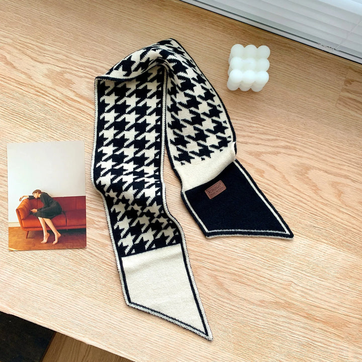 Schwarz-weißer Hahnentritt-Schal aus Wolle auf Holztisch, modisches Accessoire.