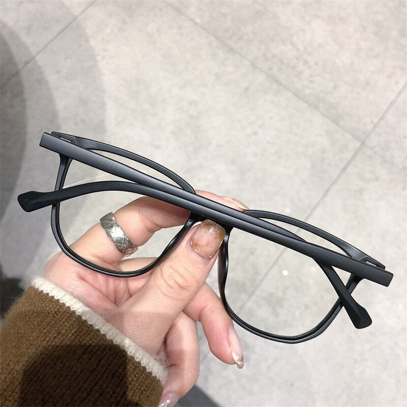 Schwarze Brille, rechteckig, Kunststoffrahmen, modisch, Unisex, Hand hält Brille.
