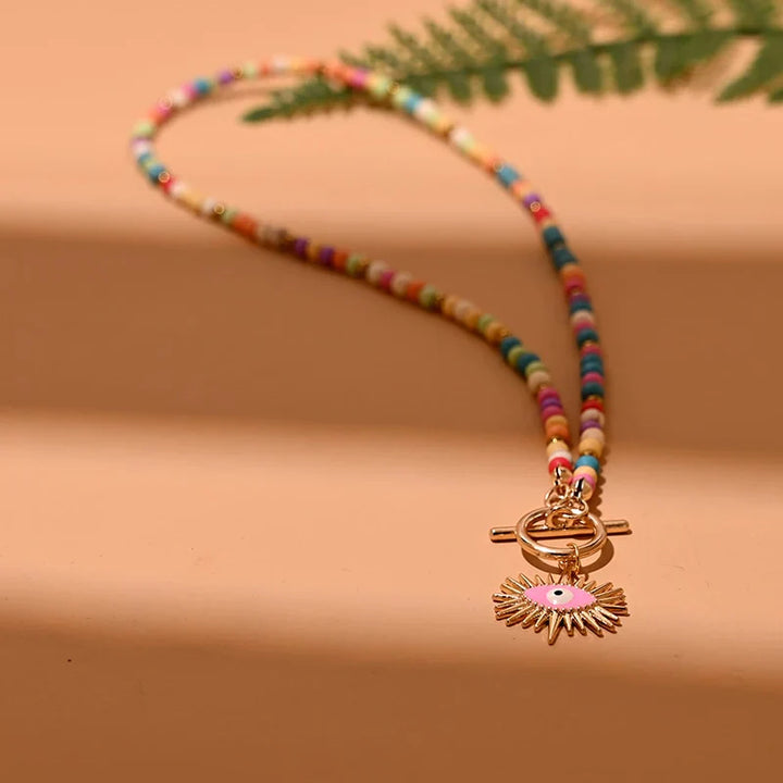 Bunte Perlenkette mit goldfarbenem Sonnenanhänger, modisches Schmuckstück für Damen.