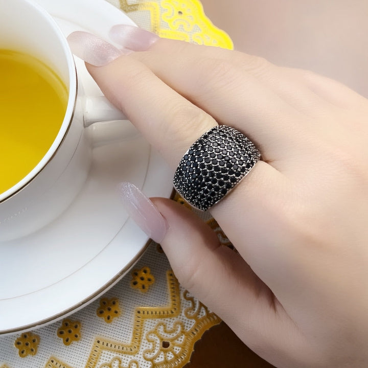 Silberner Damenring mit schwarzem Strass, elegantes Design, Hand, Teetasse, Nahaufnahme.
