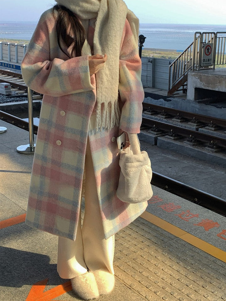 Frau im pastellfarbenen Karomantel mit Schal und Tasche am Bahnhof, Wintermode.