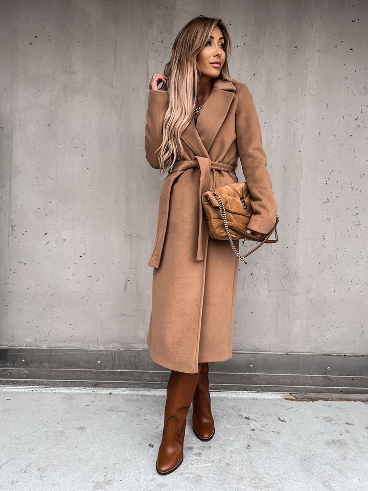 Frau in braunem Wollmantel mit Gürtel, braune Stiefel, gesteppte Handtasche, modisch, elegant.