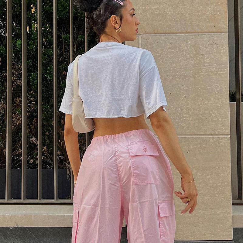 Frau in weißem Crop-Top und rosa Cargohose, modisch, urbaner Stil, Sommermode.