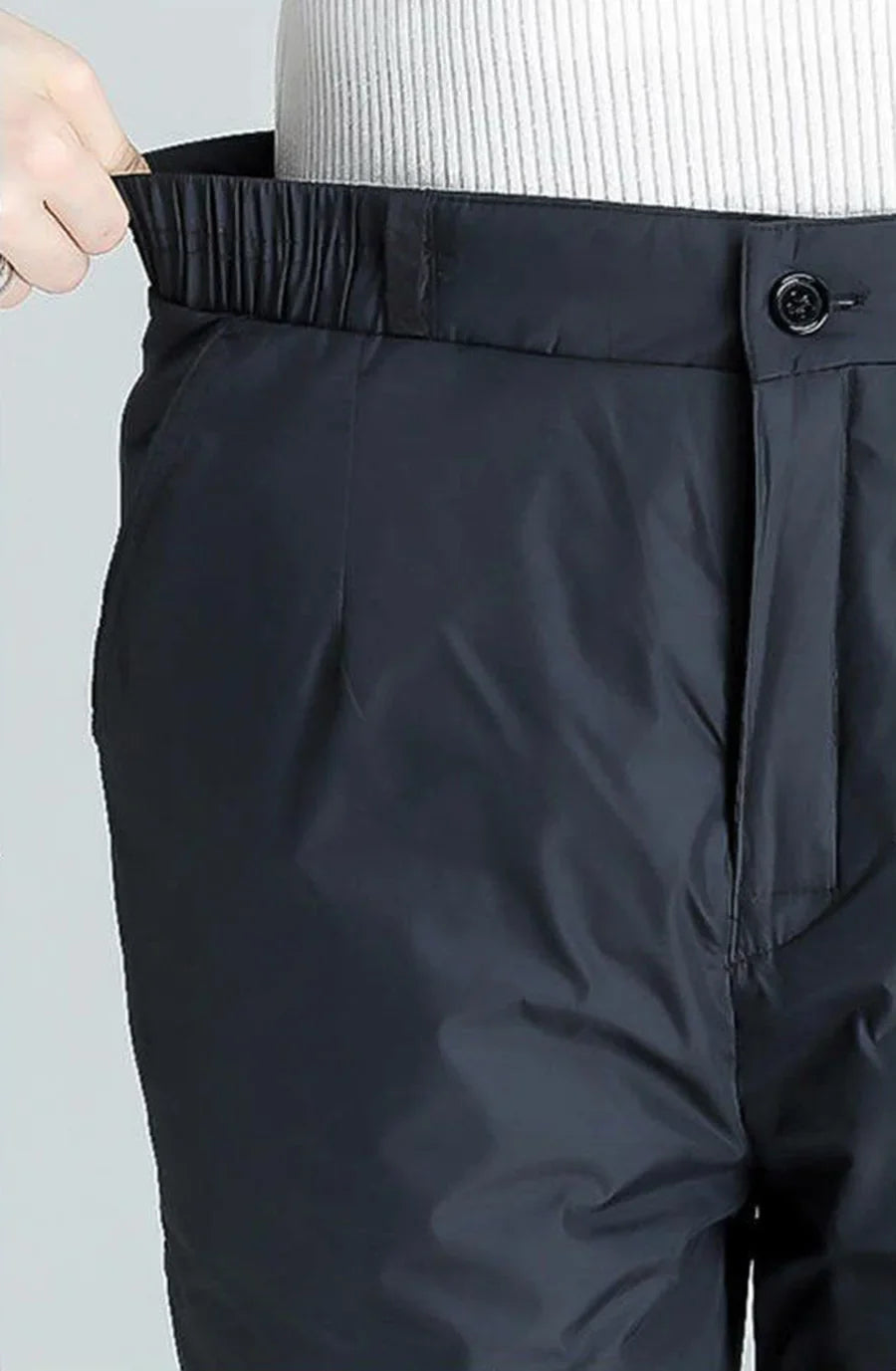 Schwarze, wasserdichte Hose mit elastischem Bund und Knopfverschluss für Outdoor-Aktivitäten.