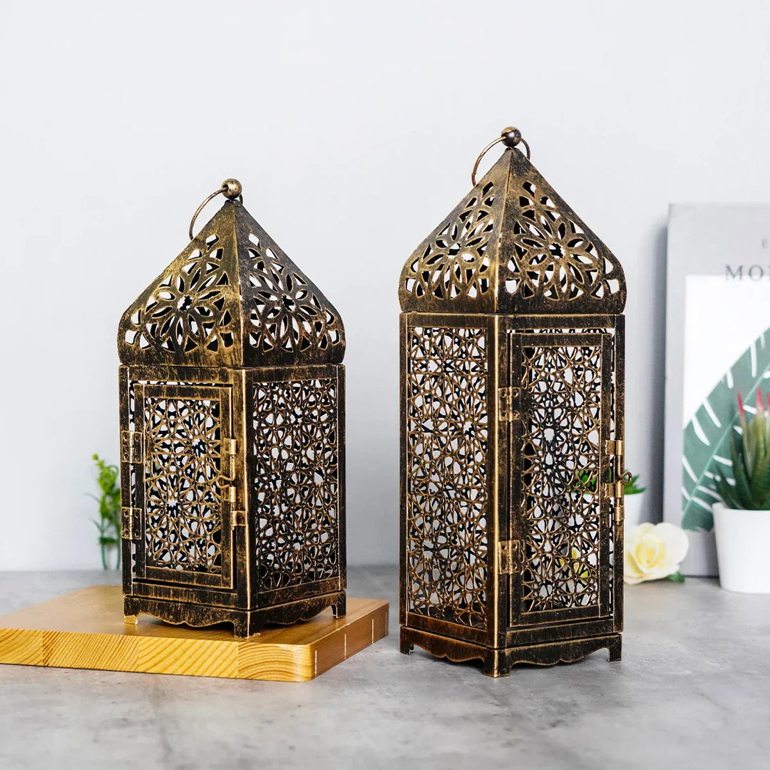 Zwei orientalische Laternen aus Metall, bronzefarben, mit filigranem Muster auf Holztisch.